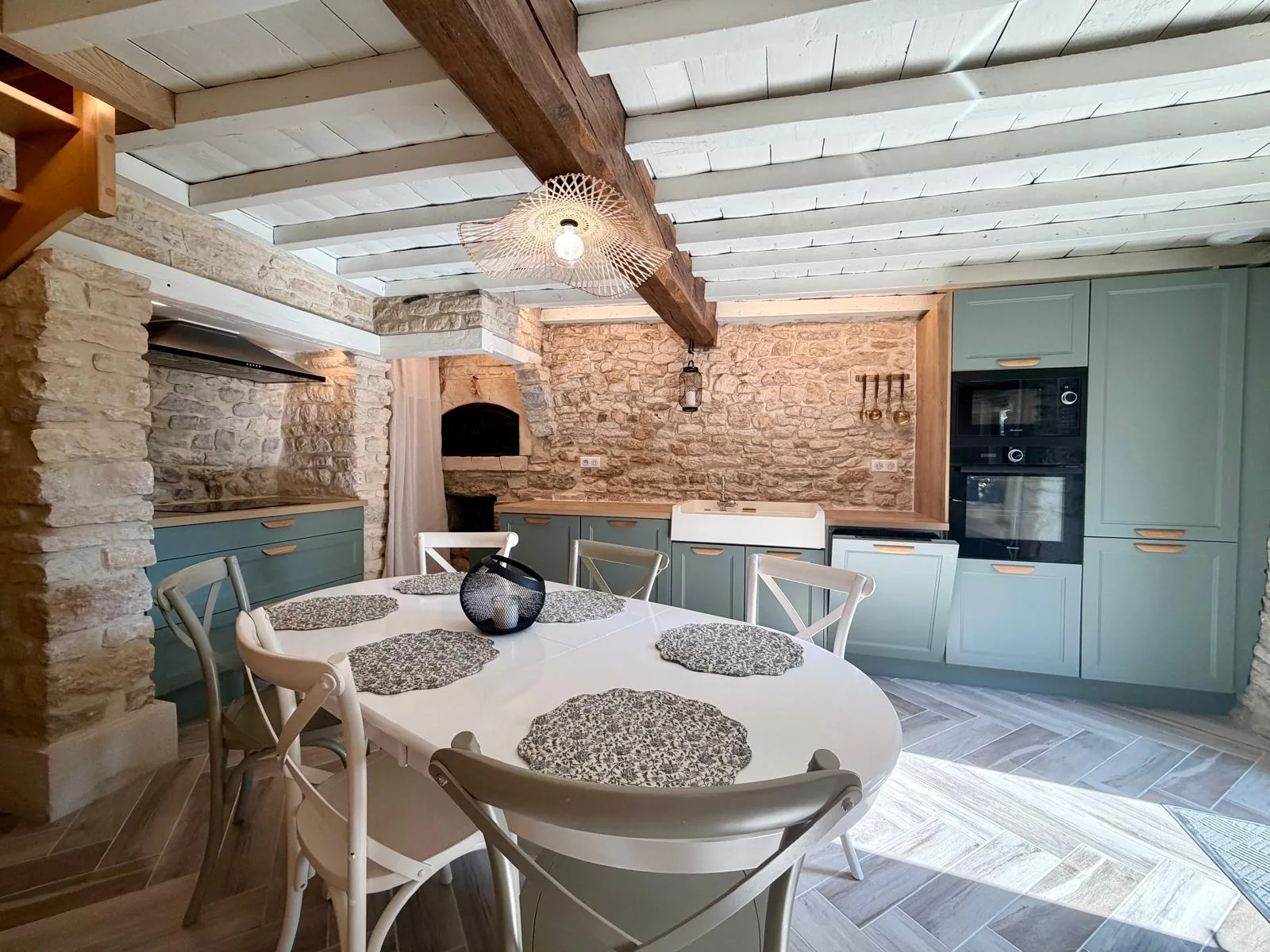 Cuisine équipée et table ronde d’une maison en pierre rénovée confiée à Como en casa